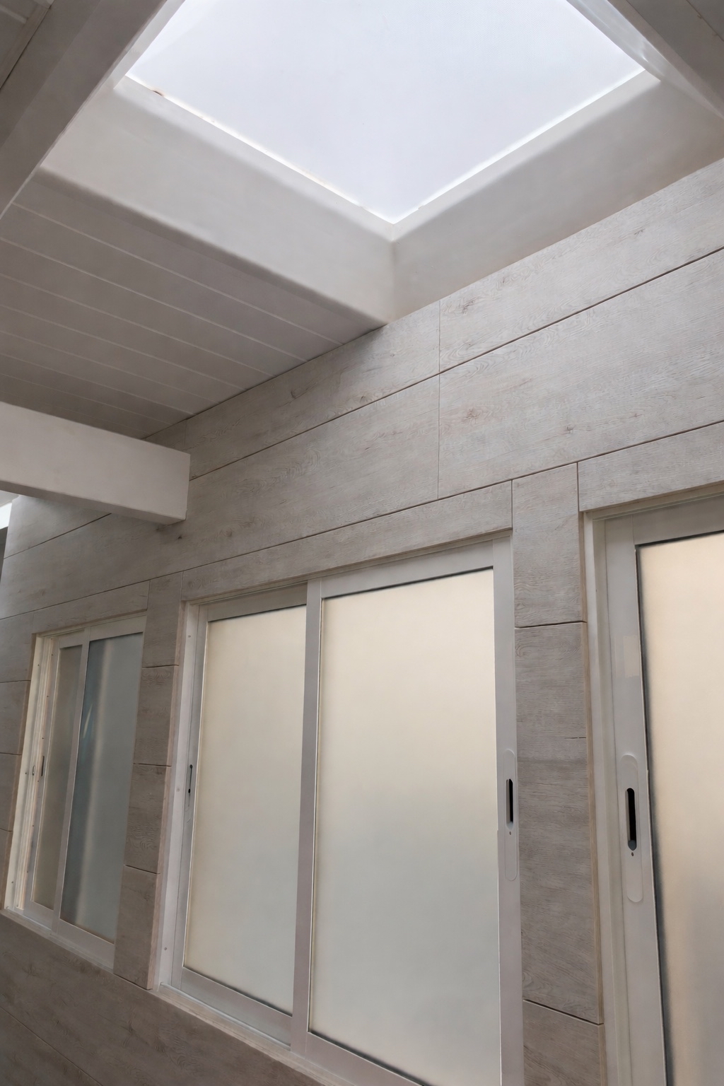 Cerramiento de patio con techo en madera blanca ,ventanas, puerta corredera y lucernarios en cristal para luz natural. Ronda Sur. Murcia. GEOFEN.