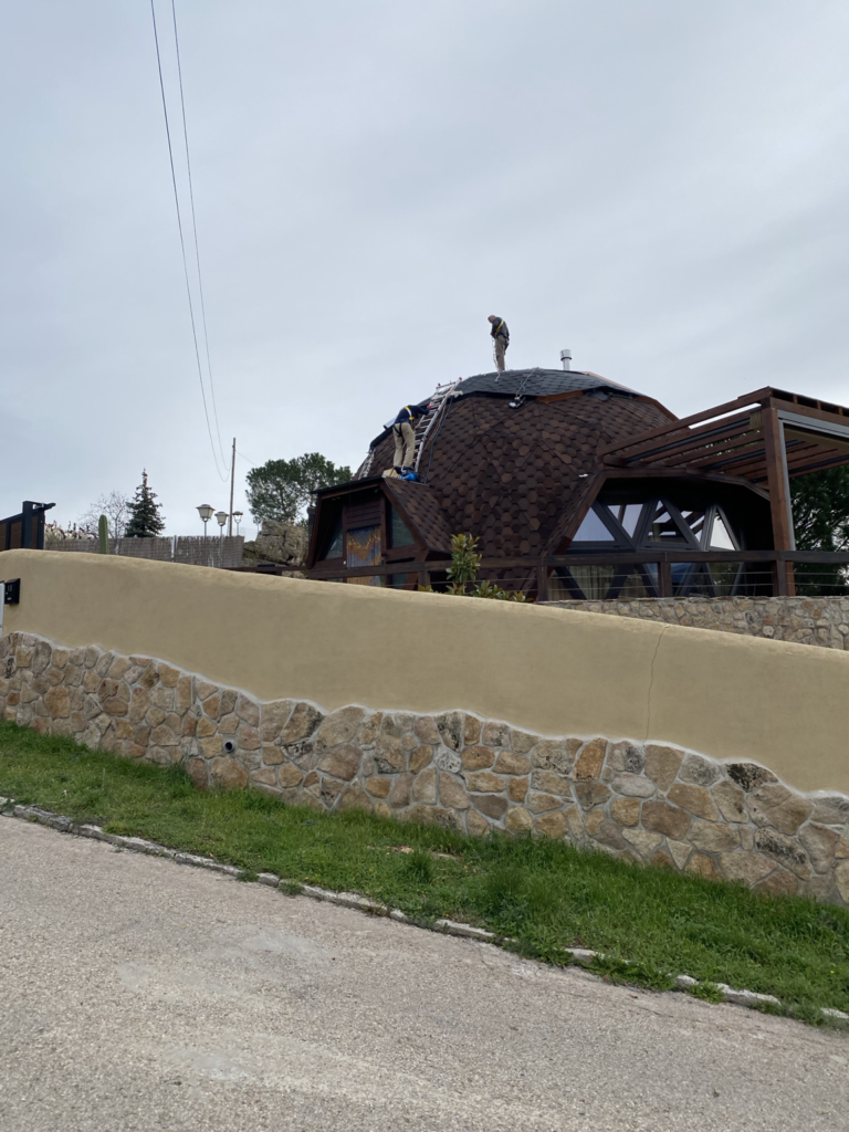 Construcción de domo geodésico con equipo técnico, trabajando en la cubierta y estructura exterior.