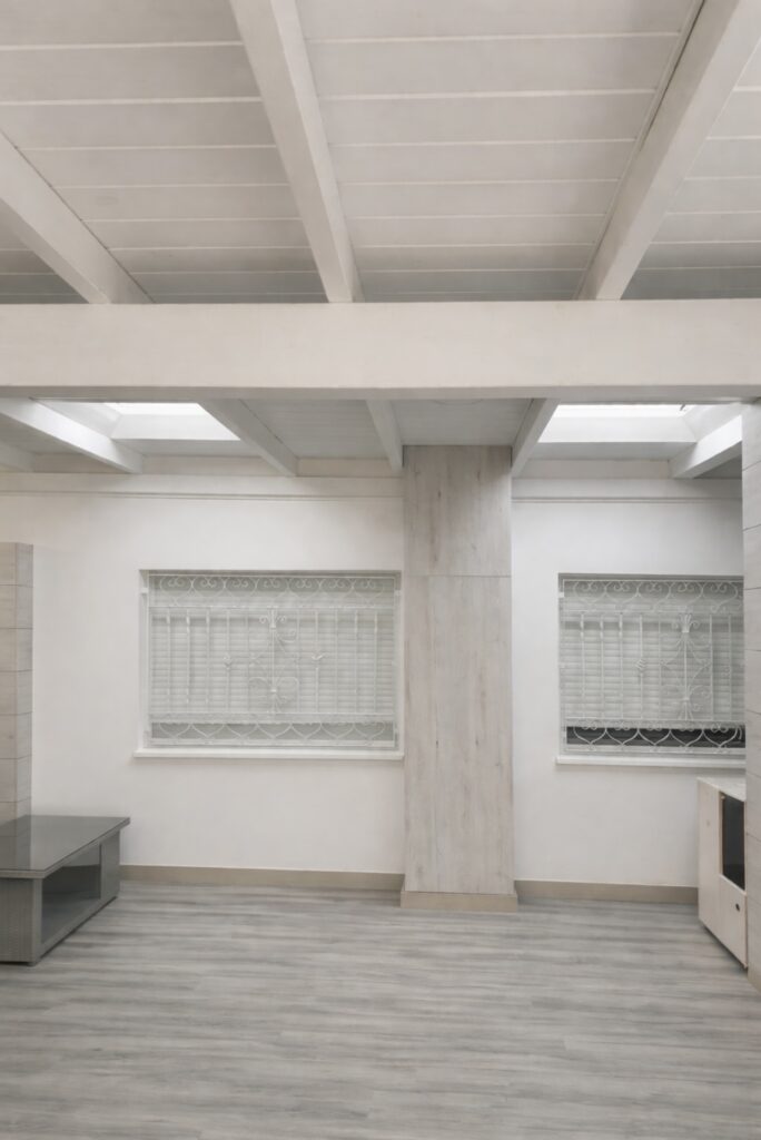 Cerramiento de patio con techo en madera blanca y lucernarios en cristal.