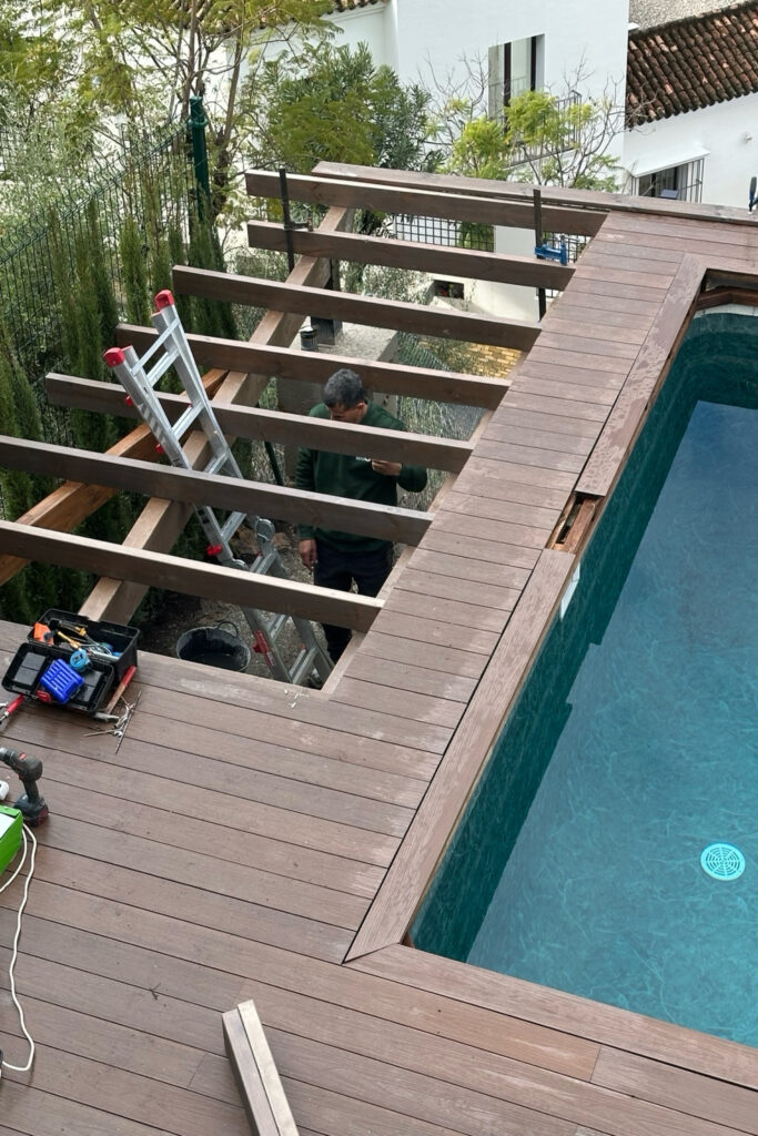 Colocación de tablas de madera tratada y pintada con lasur para estructura elevada base para tarima de piscina. Benahavís. Málaga.